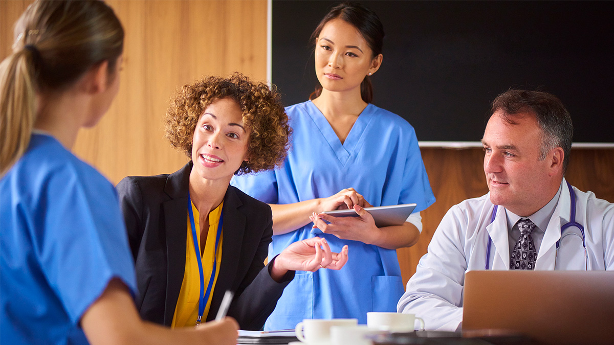 Group of healthcare professionals seated around a table discussing hepatitis outbreaks