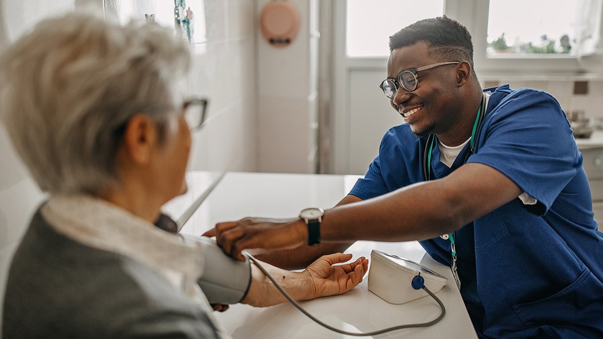 Health care professional measures blood pressure of older woman