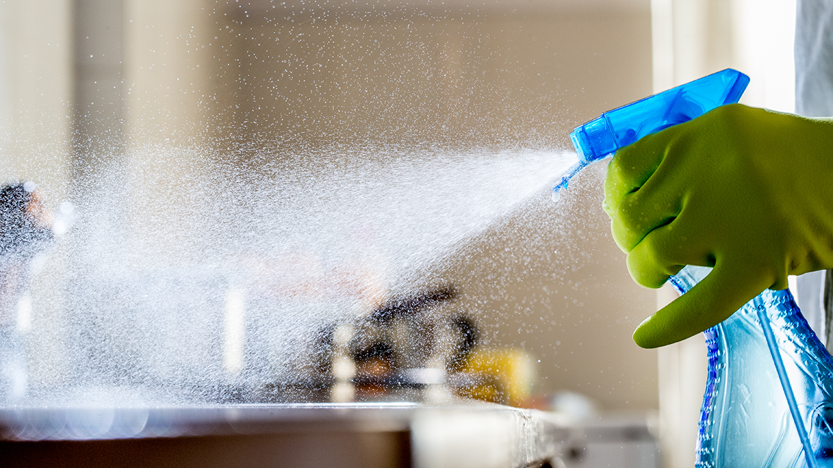 Person spraying cleaner onto a counter