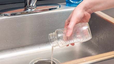 Discarding leftover milk from bottle into the sink.