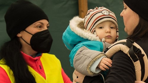 A relief worker assisting a mother and her baby during an emergency.