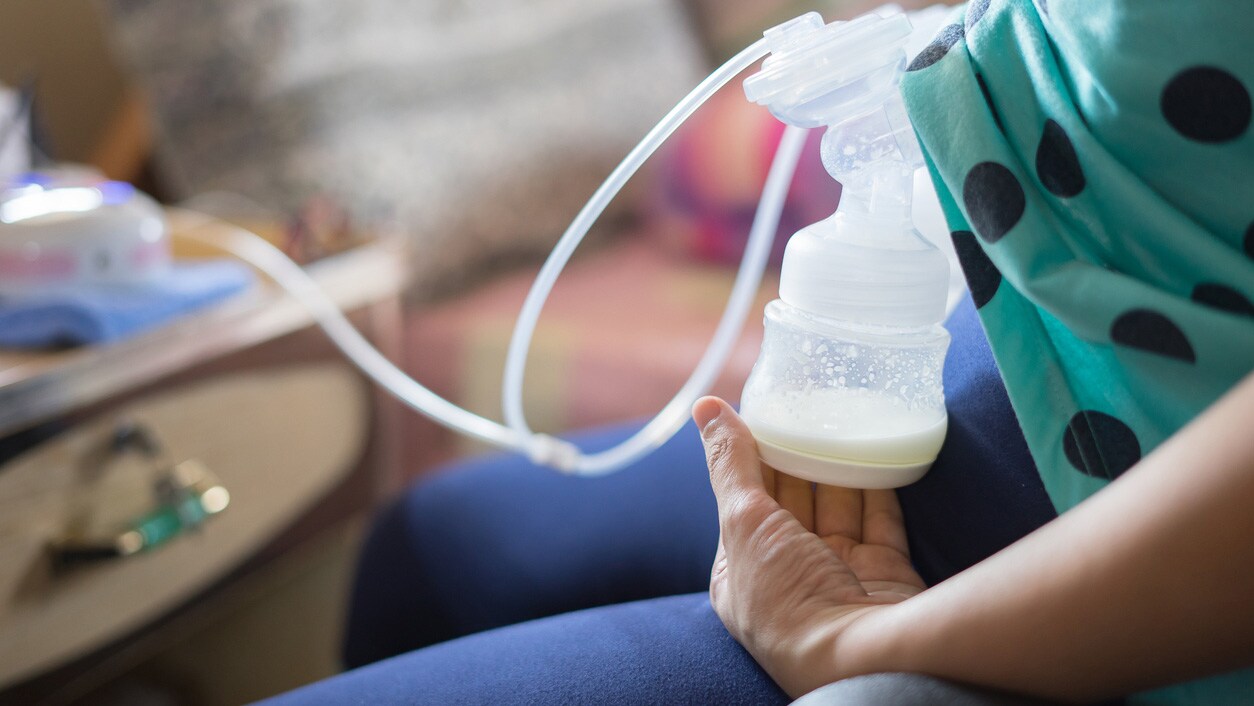 A mother using her breast pump at her office desk