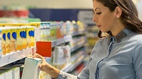 A person choosing an infant formula from a store shelf.