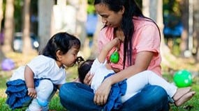 A mother breastfeeding in a park.