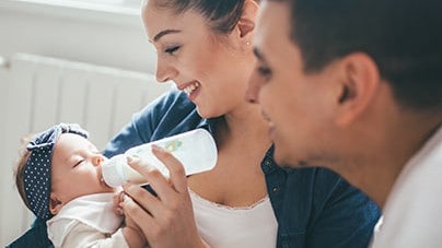 Parents feeding infant with a bottle.