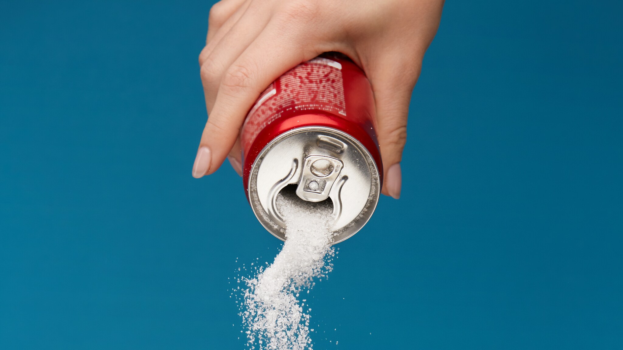 Pouring out sugar from a sugar-sweetened beverage.