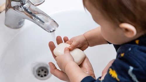 Toddler washing hands with soap and water