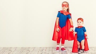 Older sister and younger brother dressed as superheroes.