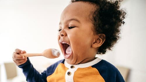 A child eating yogurt from a spoon.