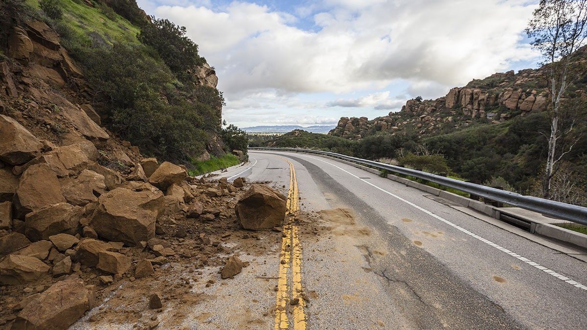 Street covered in rocks and dirt in the aftermath of a landslide.