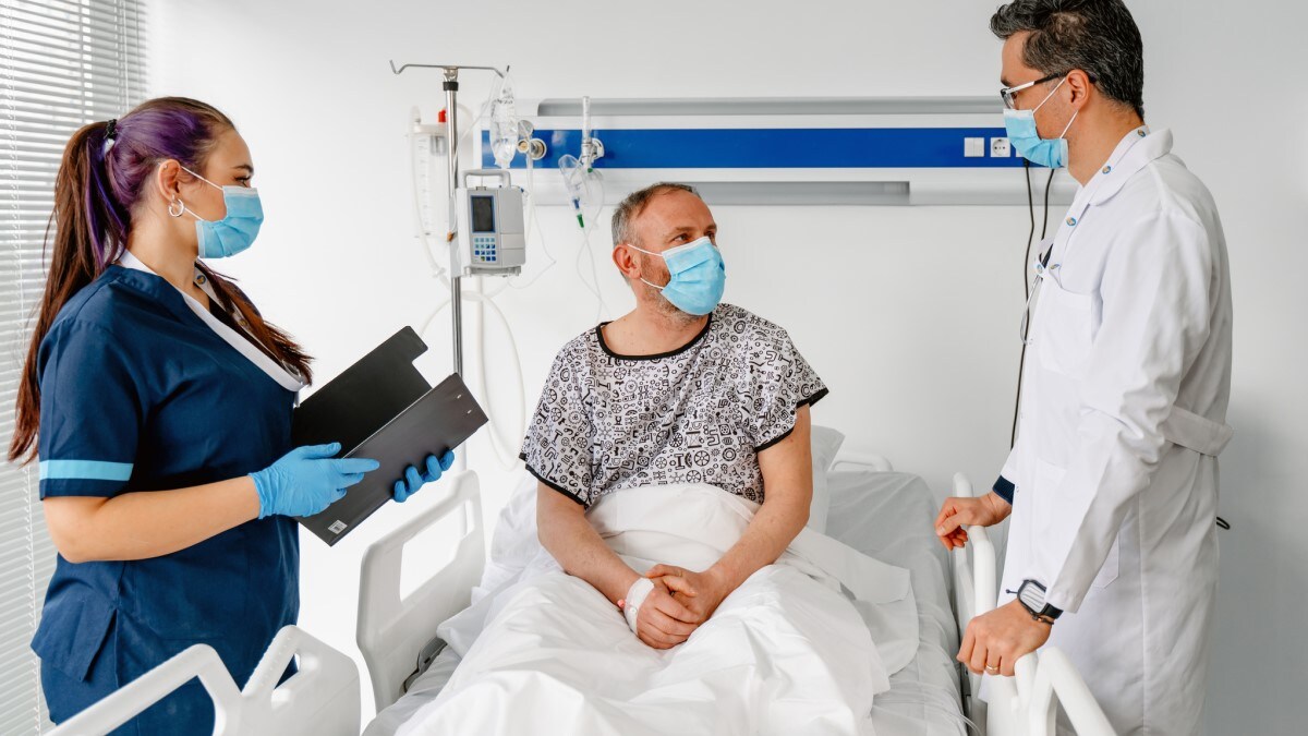 a man in a hospital talking to his doctor and nurse