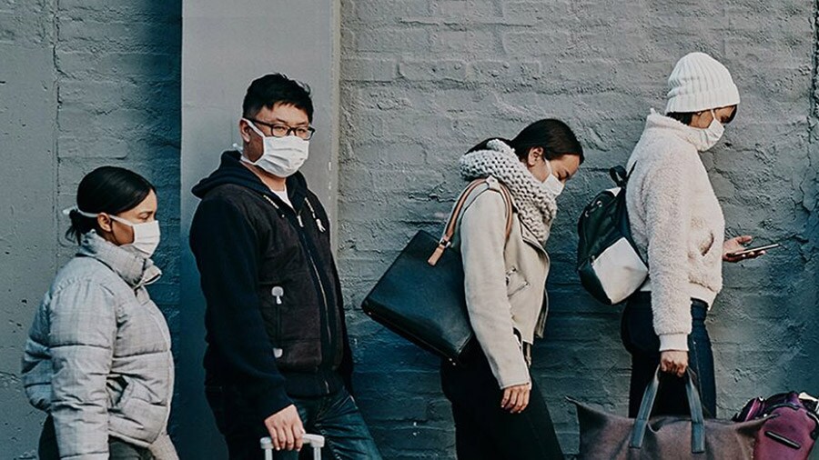 Four people standing beside a wall with luggage