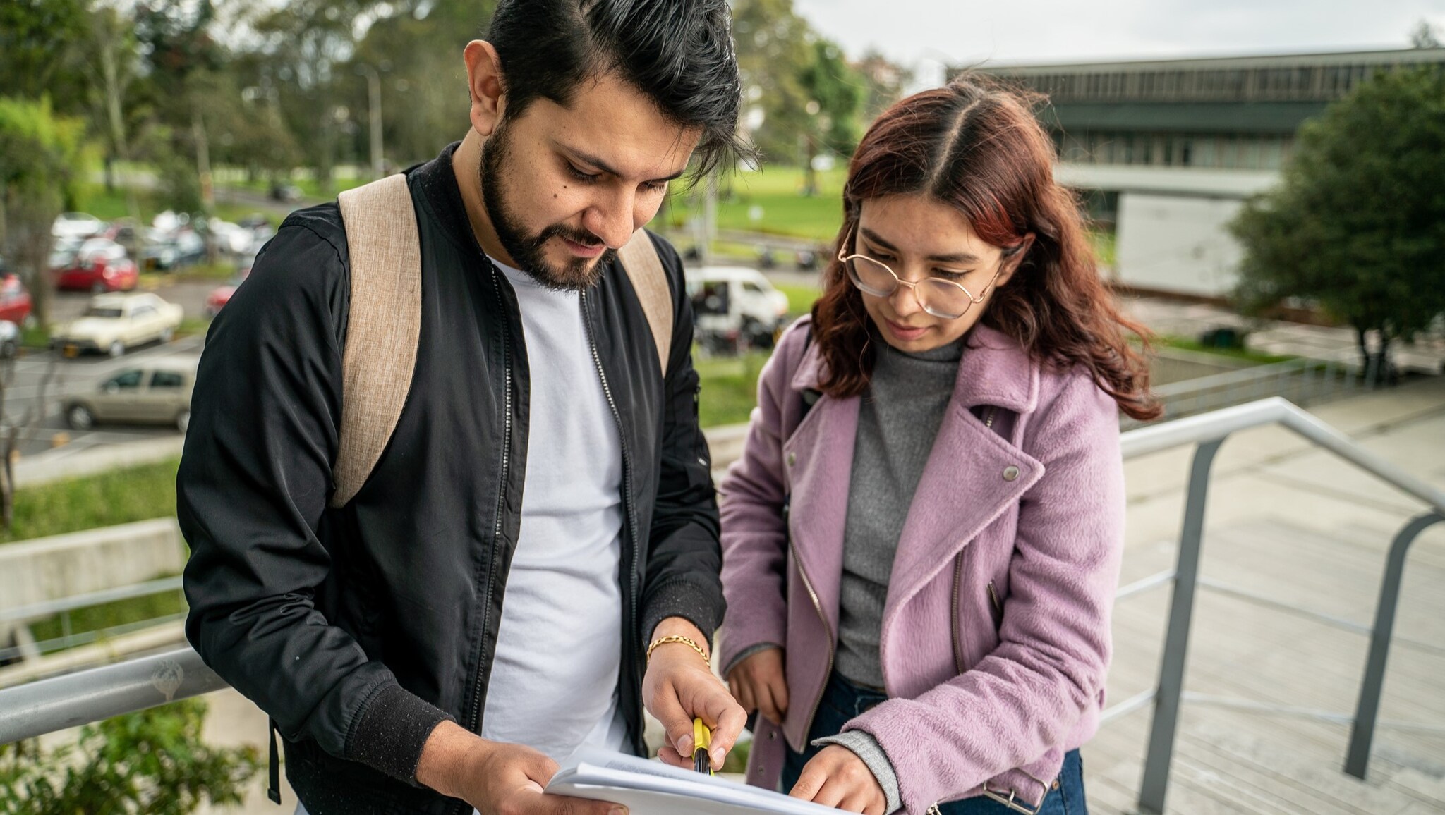 Two people outside, looking at a report.