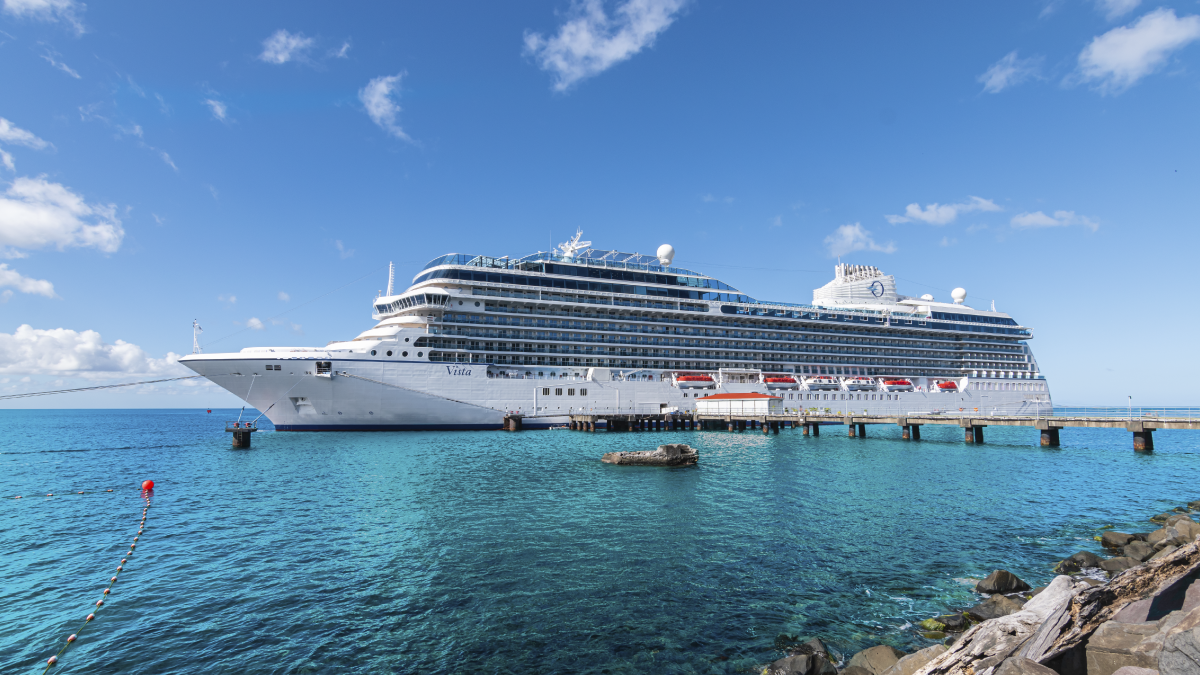 The image shows a cruise ship docked next to a pier.