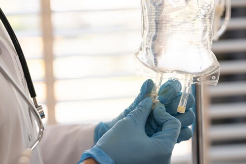 Healthcare provider wearing gloves hooks up an IV