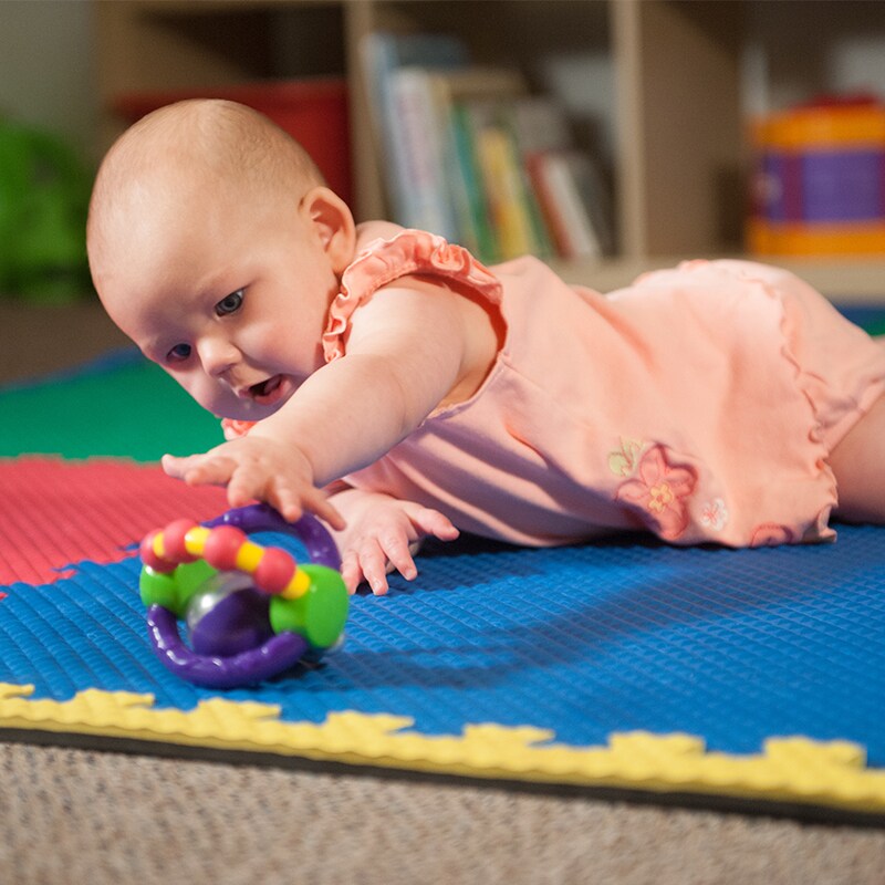 A baby reaches for a toy.