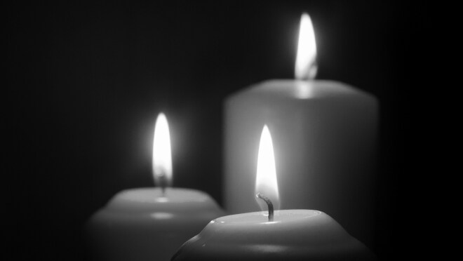 Three candles burn before a completely dark background. The text reads “Final death data for 2023 now available.”