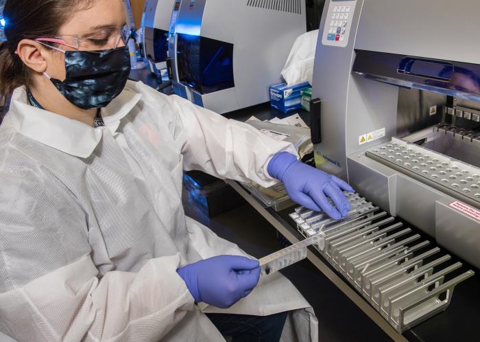 Female scientist preparing samples for Real-Time Reverse Transcriptase (RT)–PCR analysis of SARS-CoV-2 specimens