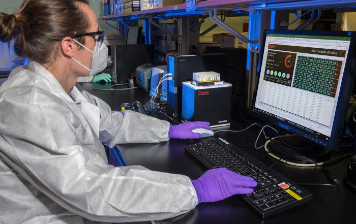 Scientist sitting at desk reviewing results on a computer