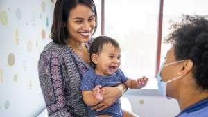 Mom holding baby and smiling at doctor