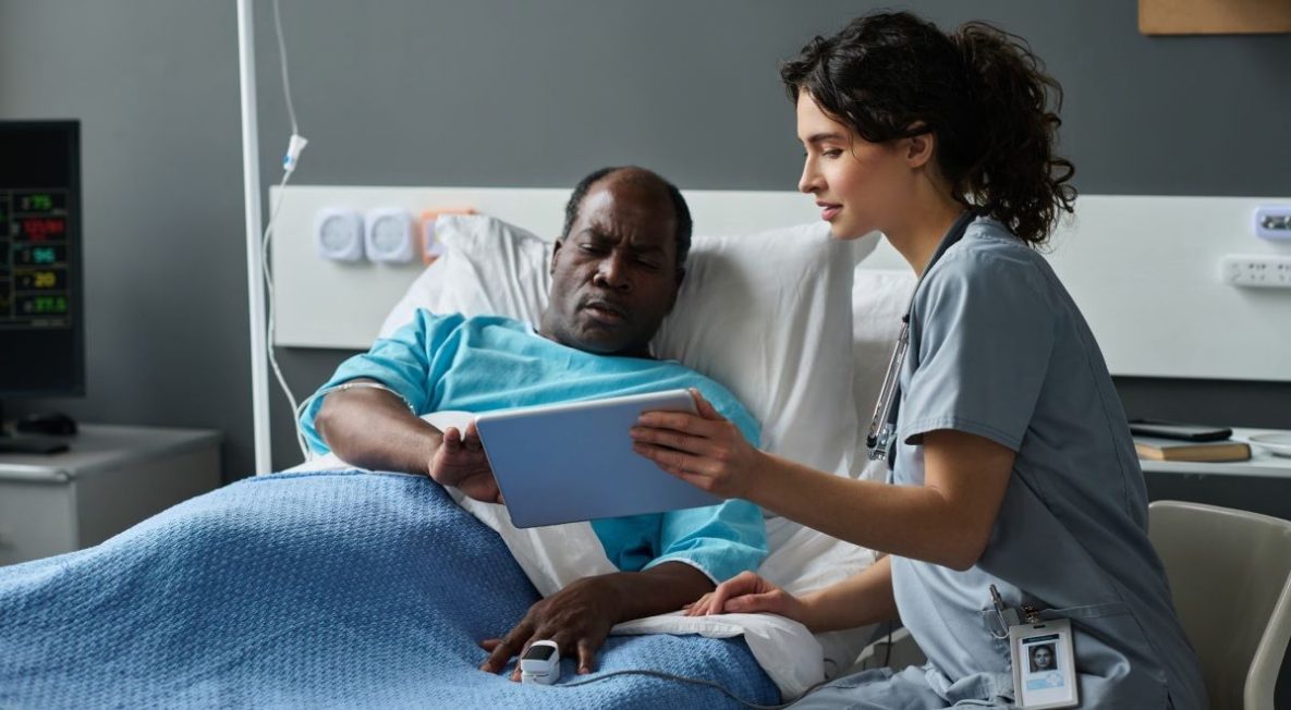 Hospitalize senior man and his female doctor using digital tablet at the clinic.