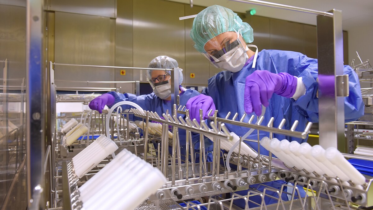 Two women work in a hospital as medical hygiene technicians dressed in protective clothing.