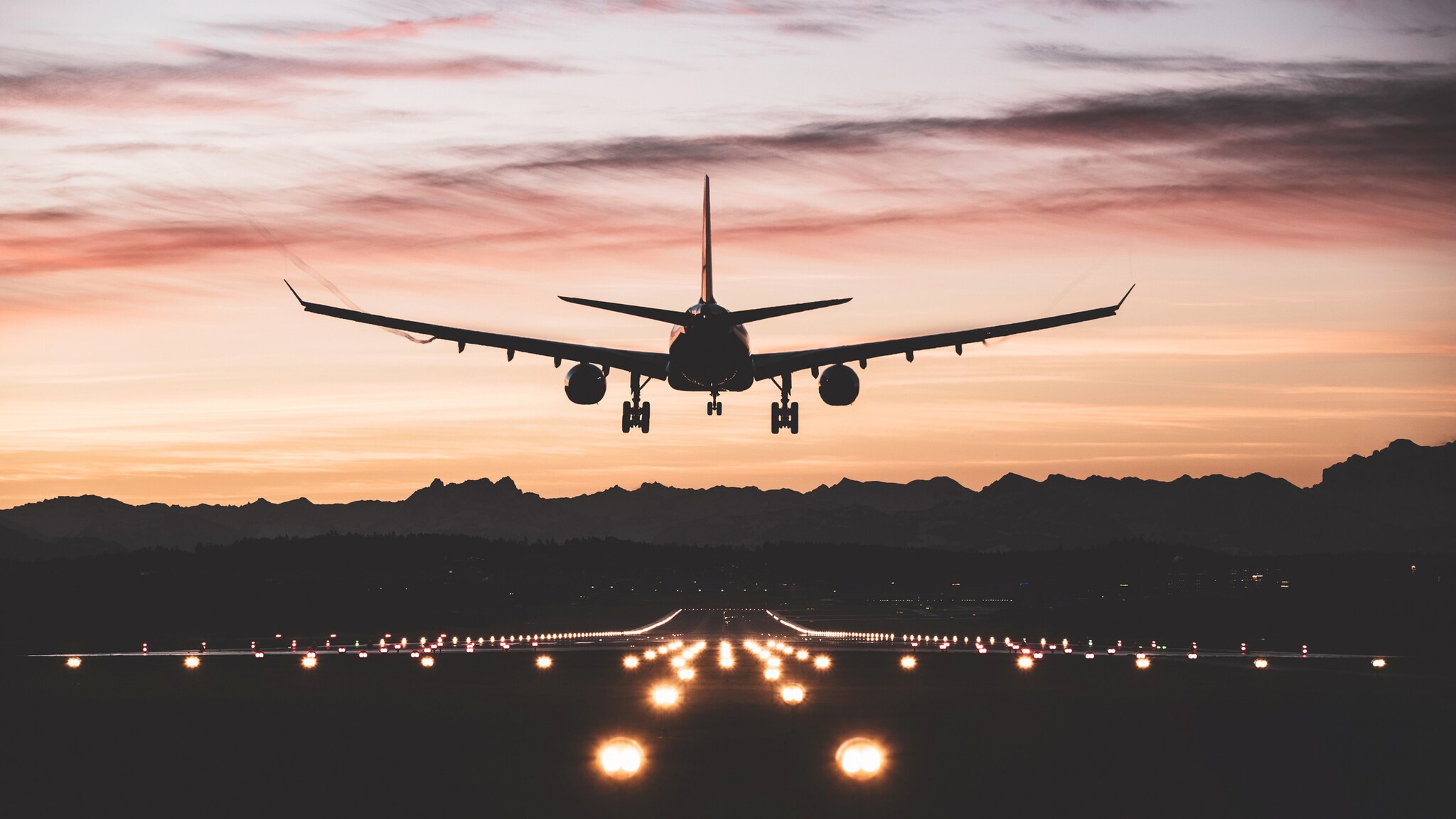 A commercial aircraft landing at an airport during dusk.