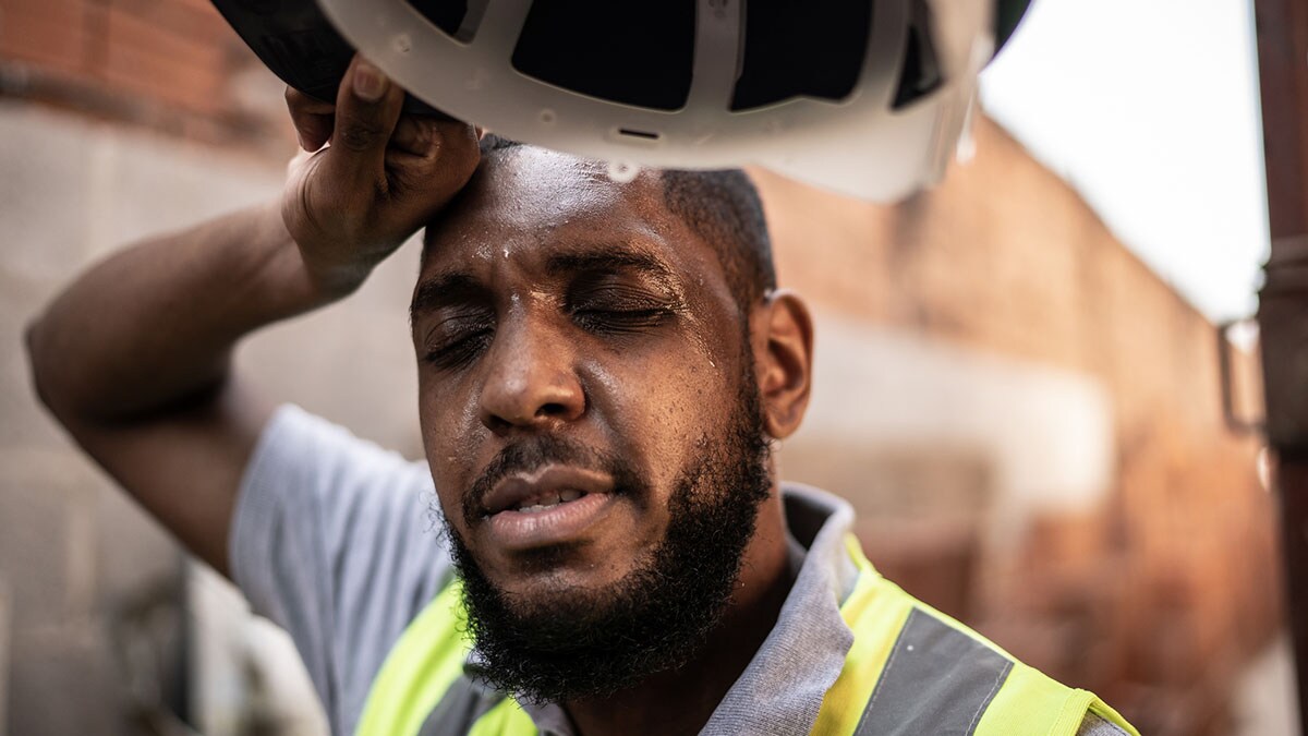 African American male construction worker sweating while taking a rest break on a construction site.