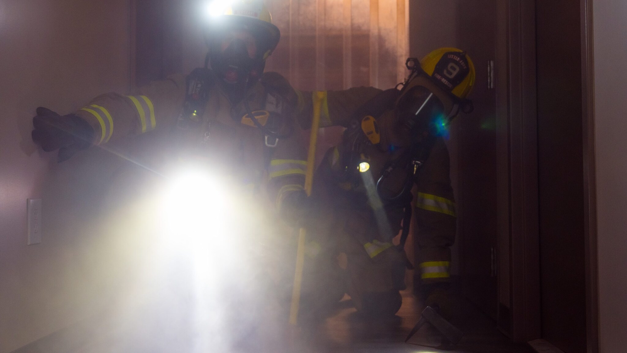 Two firefighters are searching with flashlights.