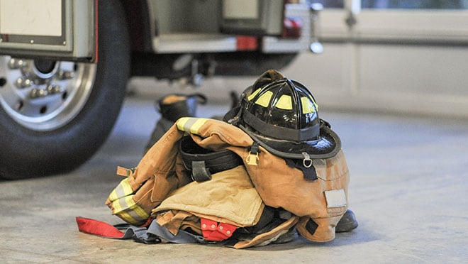 Image of helmet, jacket and boots sitting on floor beside a truck.