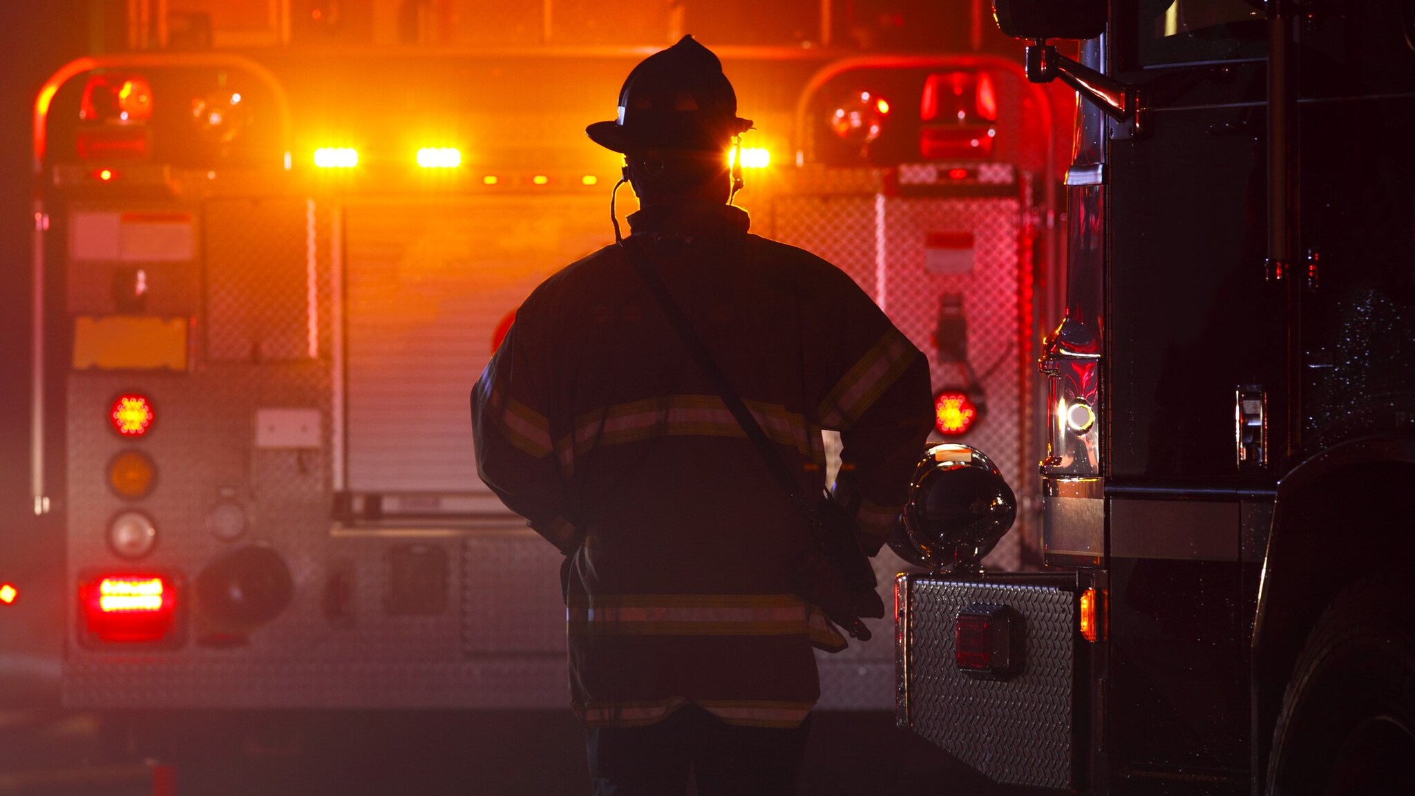 A firefighter walks towards a firetruck.