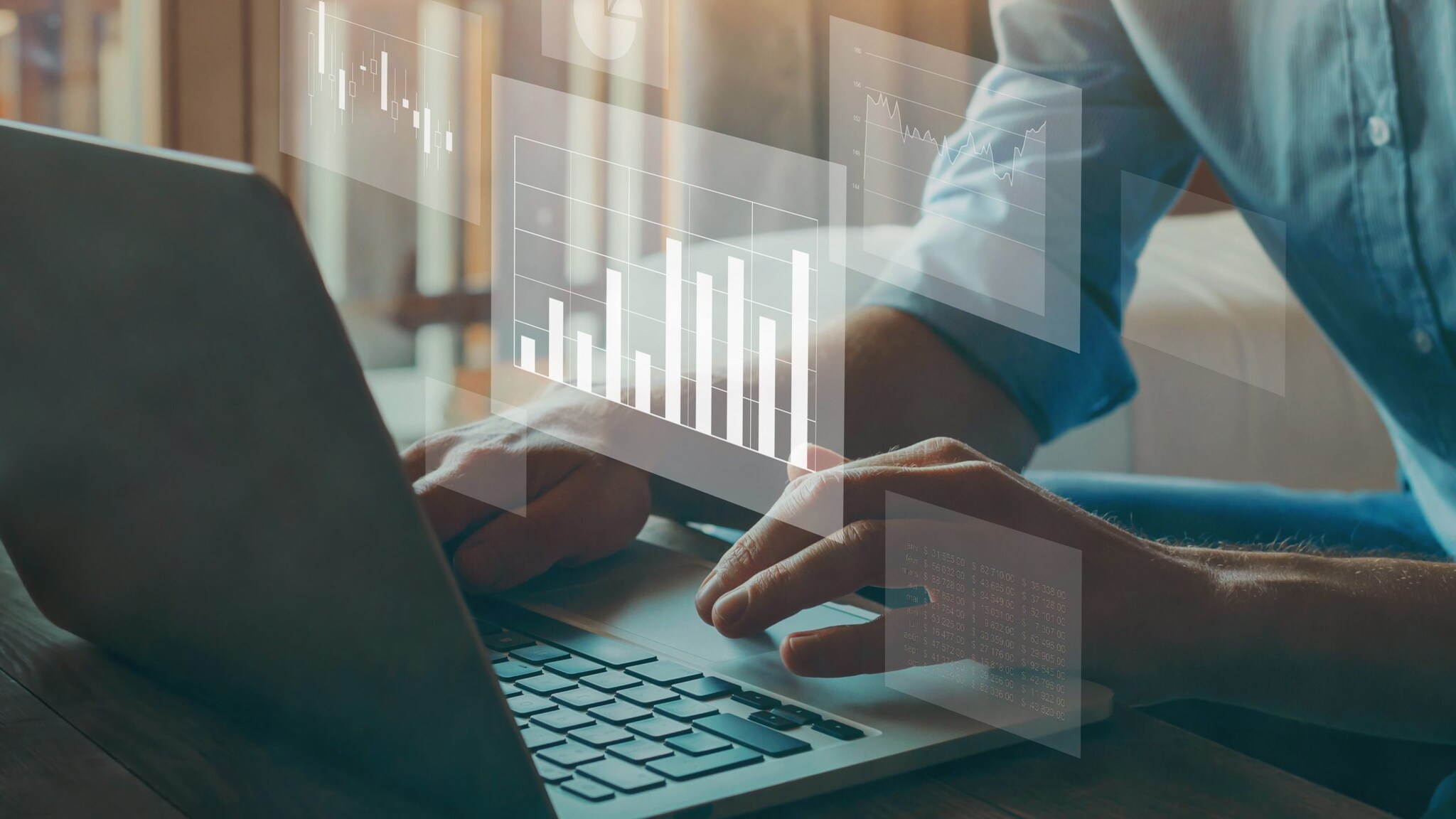 Hands typing on a laptop with small, transparent images of different charts and graphs.