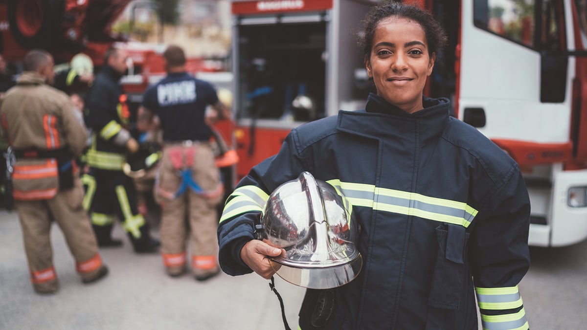 Pregnant firefighter in foreground, with other firefighters in the background.