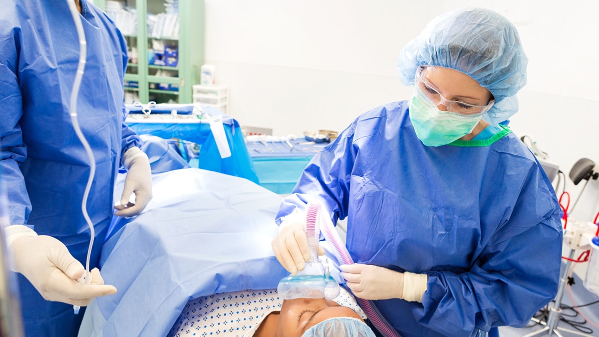 Healthcare workers wearing PPE and providing anesthetic gas to patient