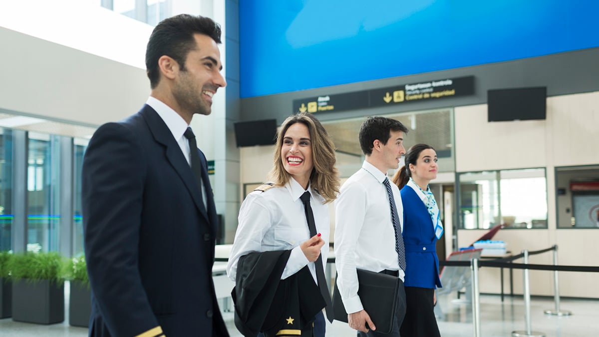 Male and female aircrew members walking in an airport.