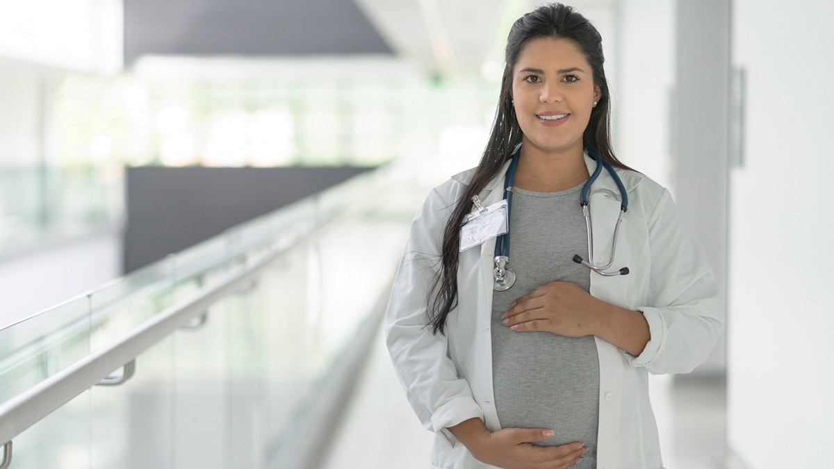 Trabajadora de la salud embarazada que lleva un estetoscopio.