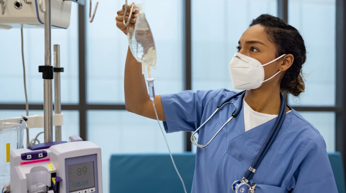 Nurse at the hospital putting an IV drip on a patient.