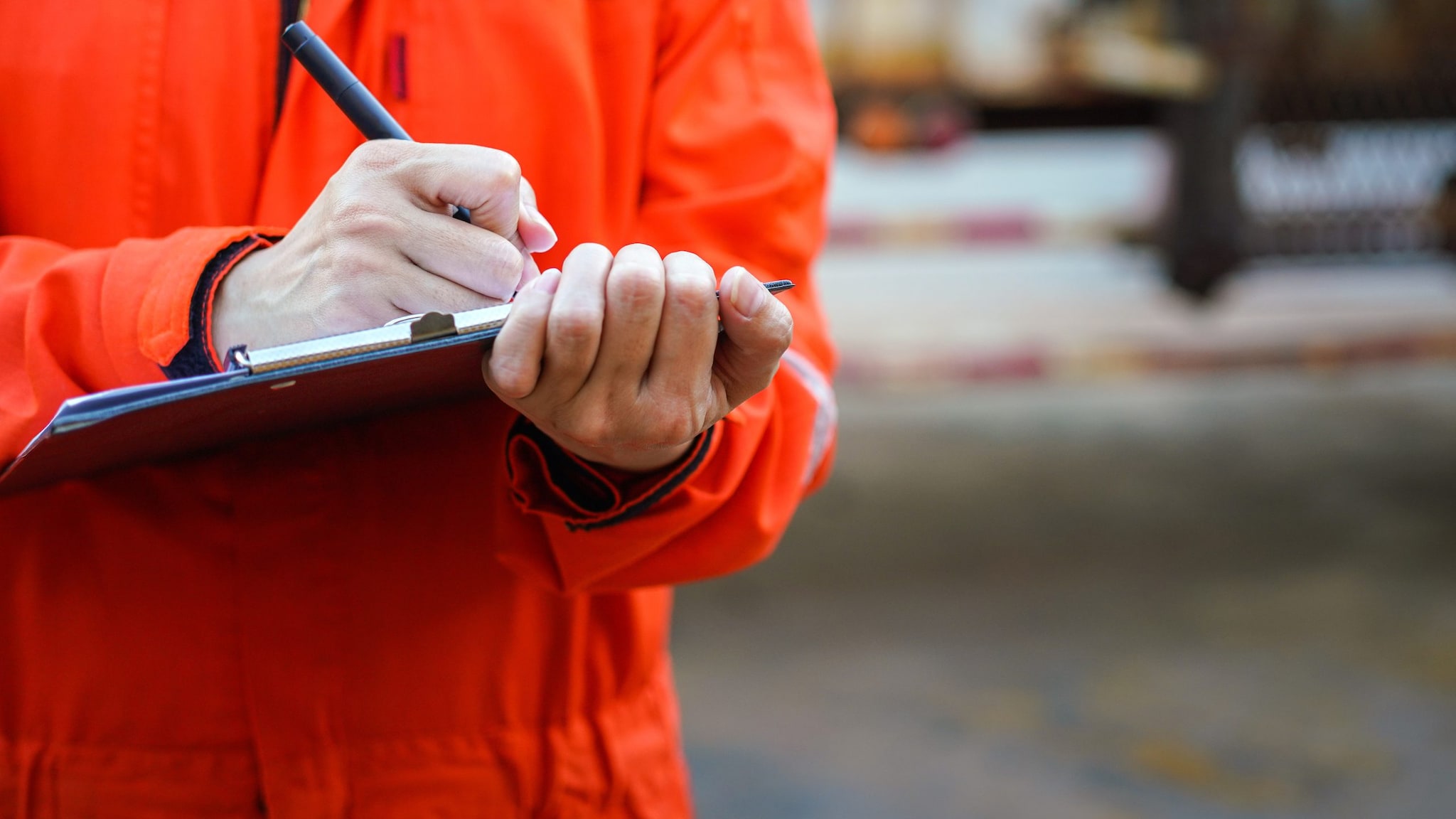 A safety officer is writing on the checklist document during safety audit workplace at the factory.