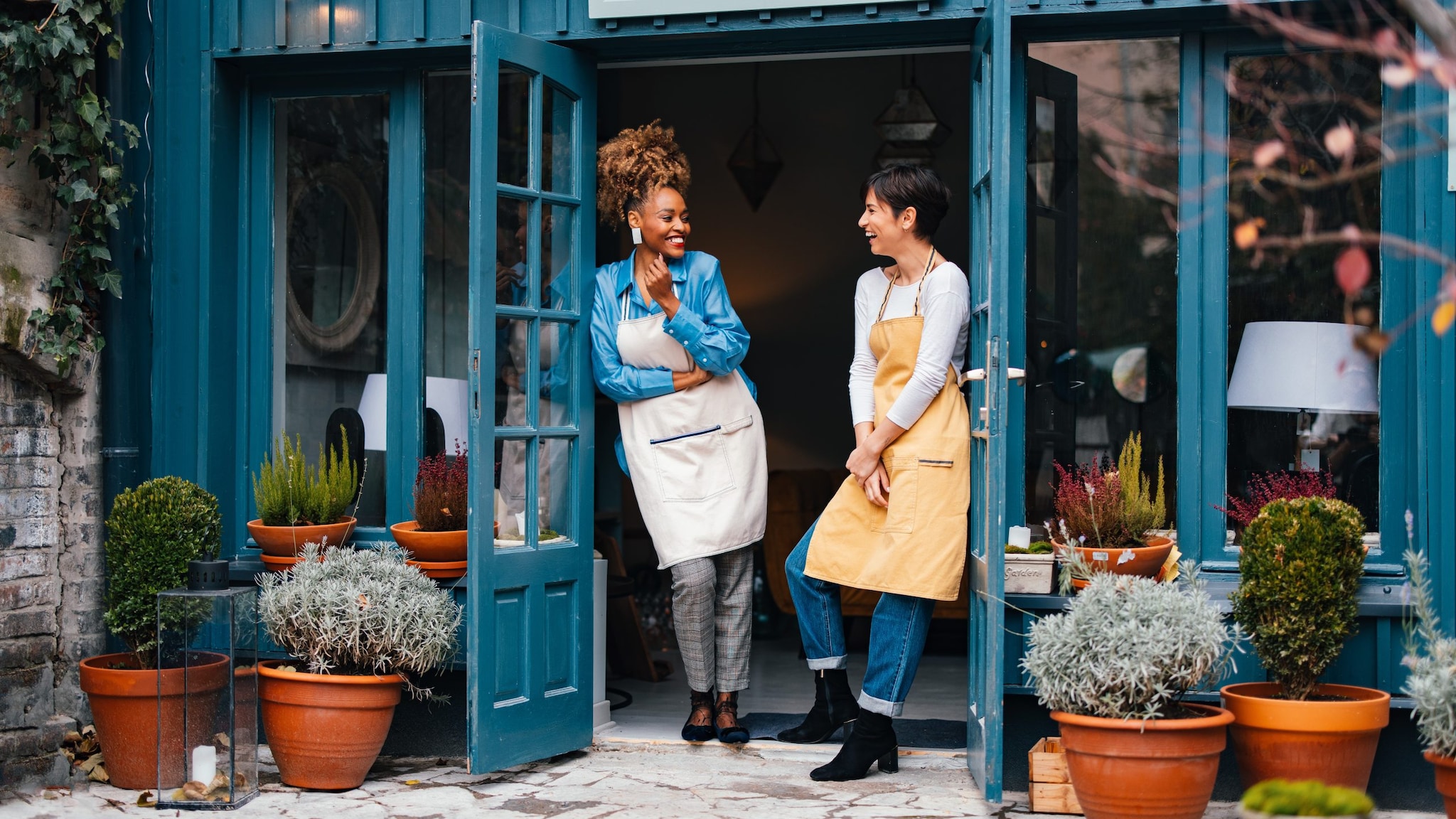 African-American woman and her employee talking and laughing while standing at door of the store.