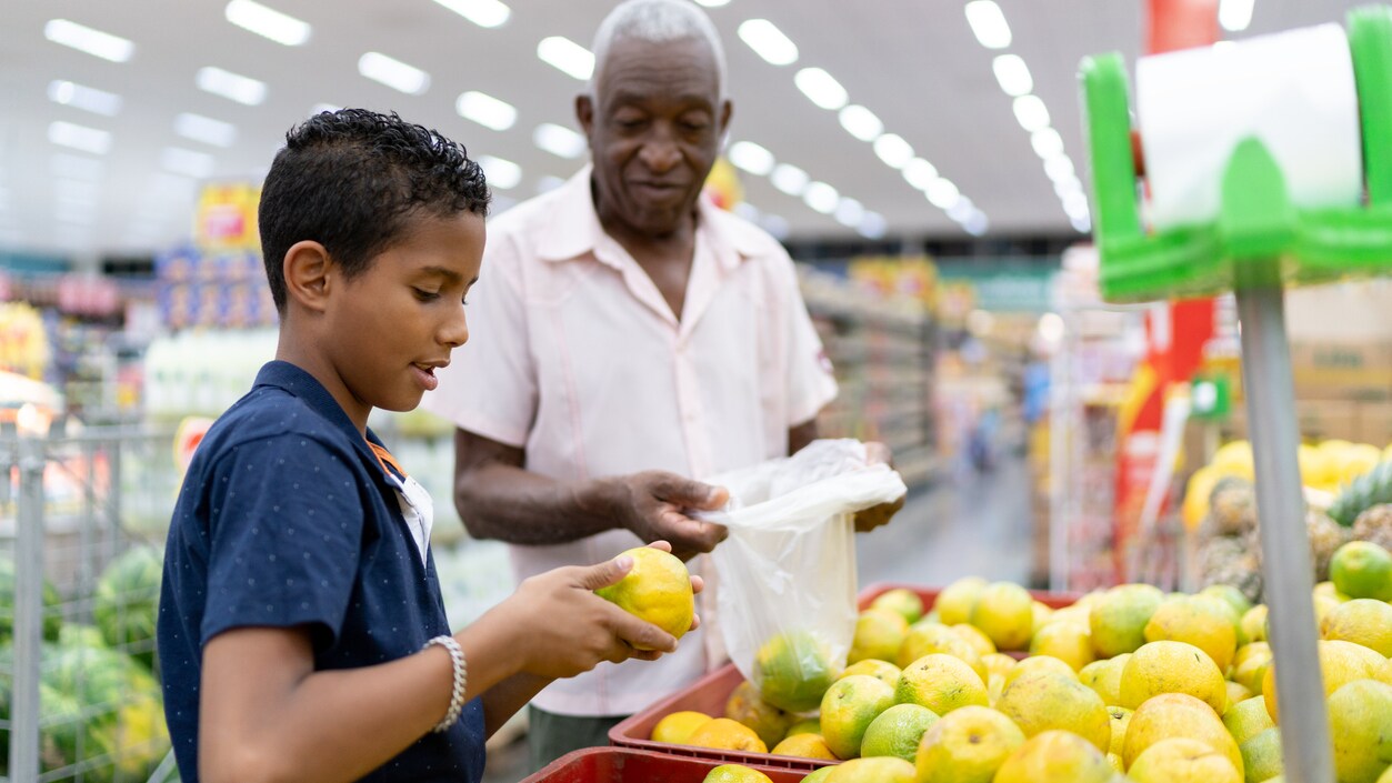 Granddad and grandson picking produce in grocery store.