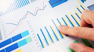 Finger pointing to a generic graph page with several colorful graphs present.