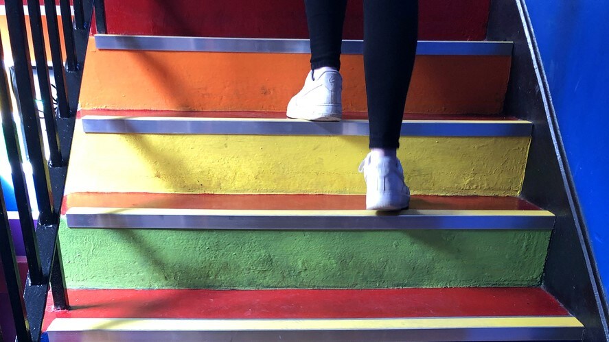 A person's feet walking up a colorful staircase.