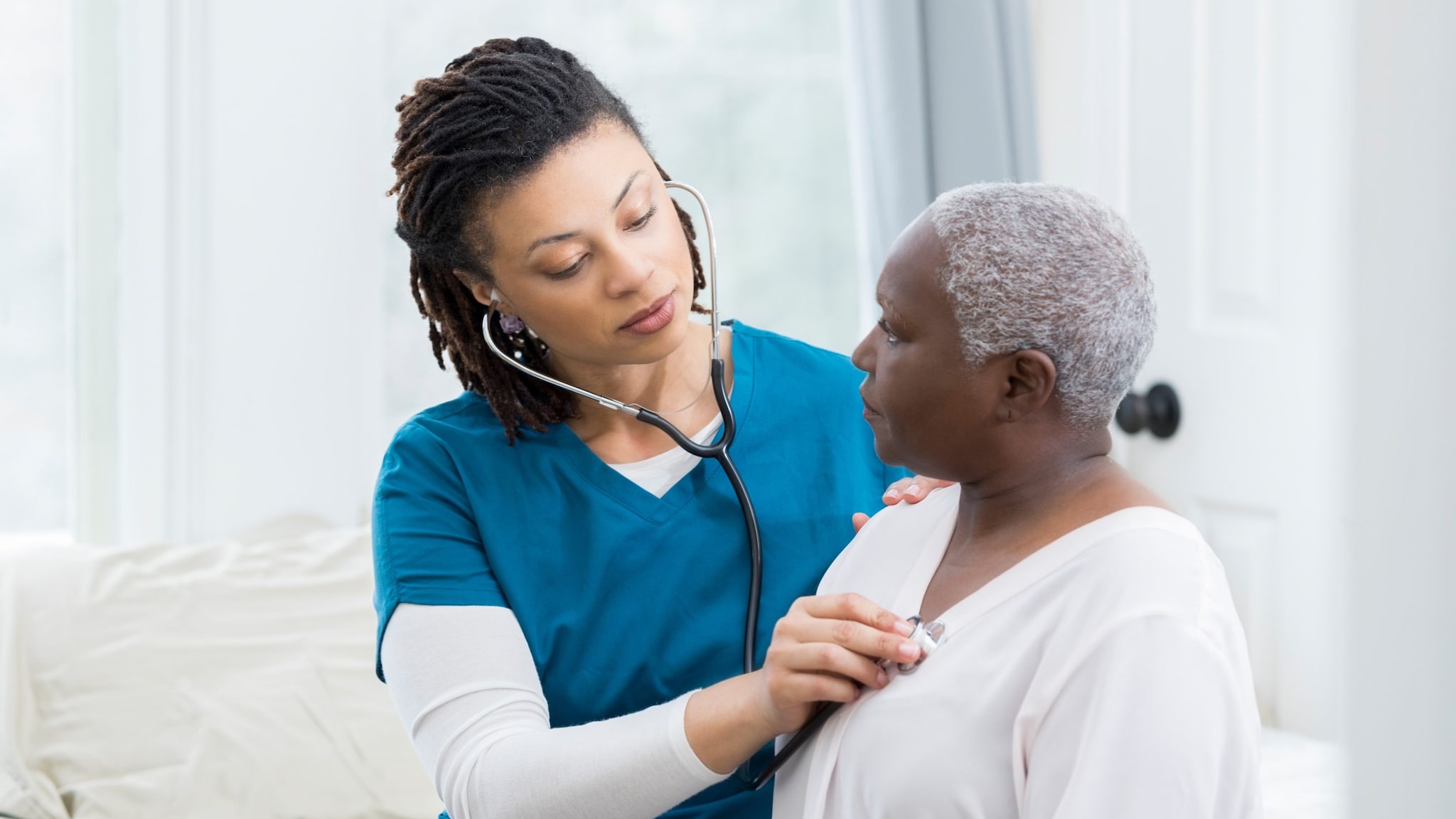 Healthcare provider is using stethoscope to check patient.