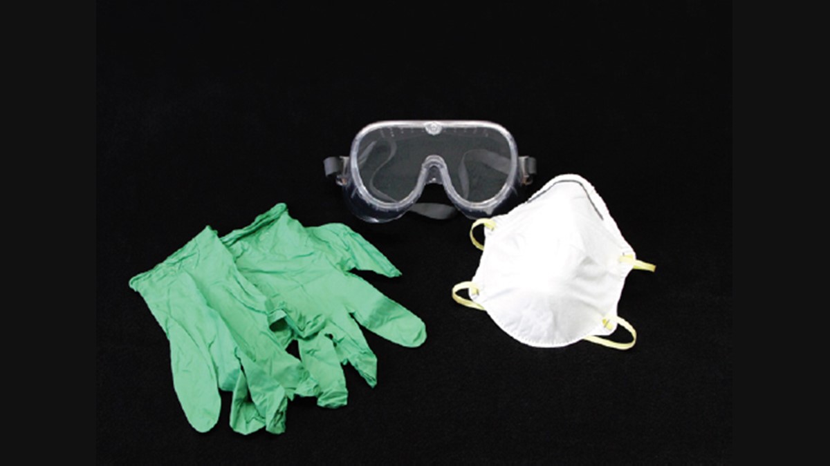 A pair of safety goggles, a dust mask, and a pair of rubber gloves on a black background