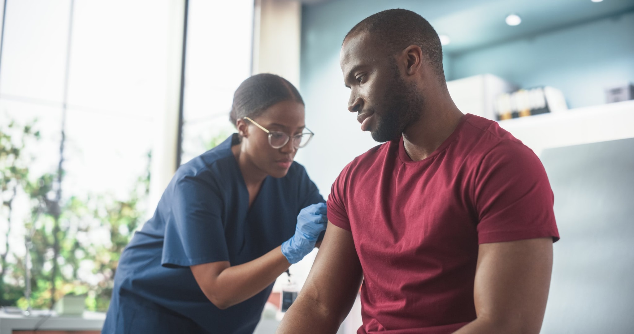 An African American man receives an injection from a healthcare worker