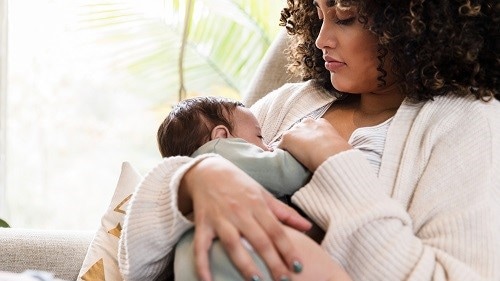 Mother watches as baby breastfeeds