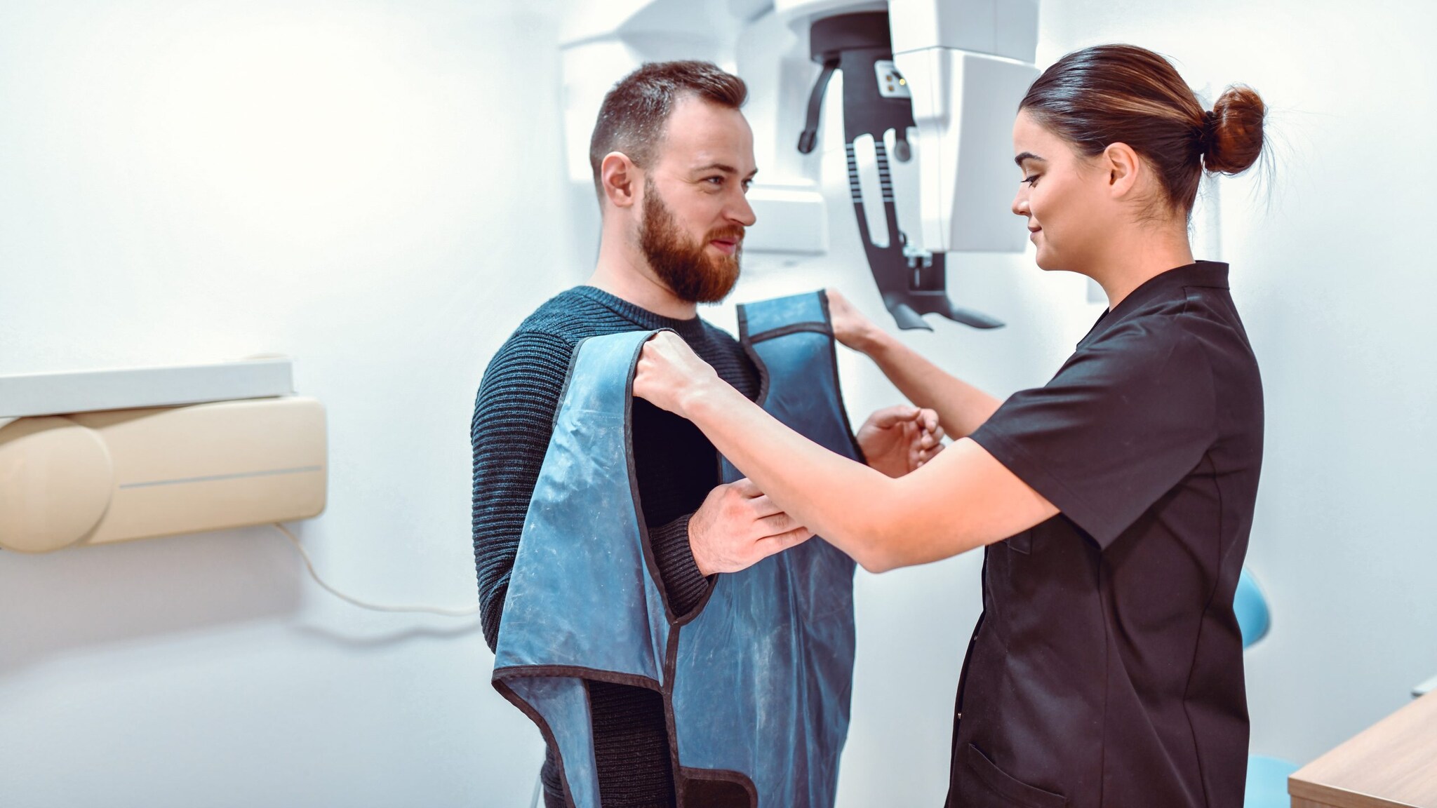 Female dental radiologist preparing male patient for dental computer tomography