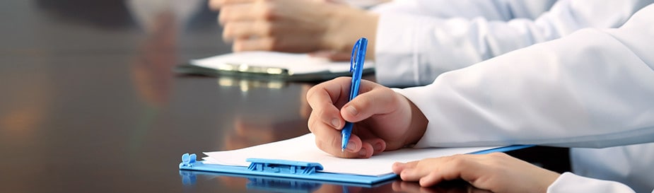 People taking notes in a meeting room.