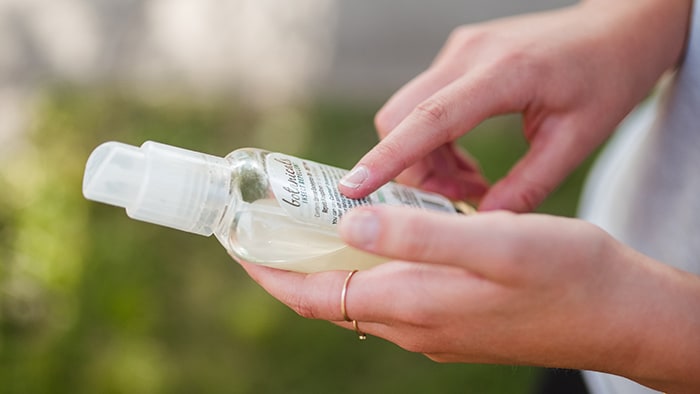 Person holding a bottle of insect repellant.