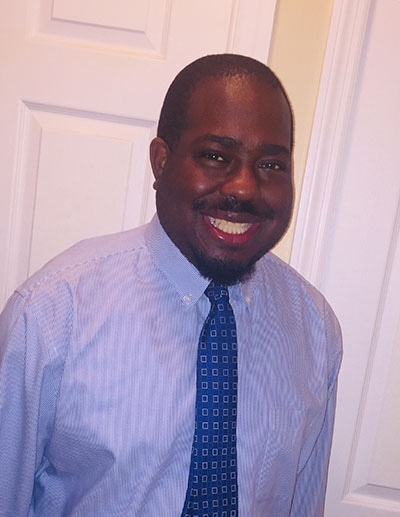 A picture of Harry Williams, Junior wearing a button-down shirt and tie and smiling